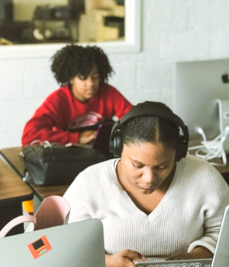 Two students of color working on computers in a classroom