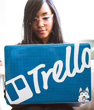 Asian female working on computer with Trello sticker