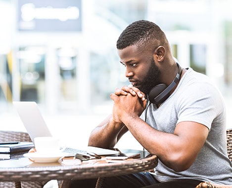 Black male sitting at a computer with coffee