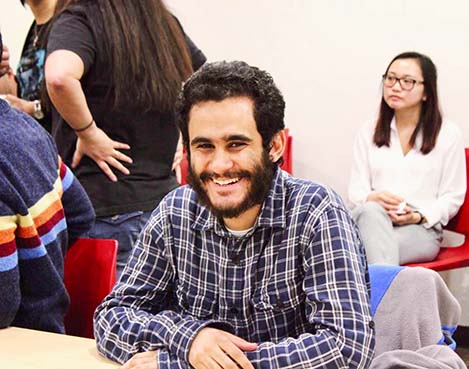 Smiling male student sitting in classroom with peers
