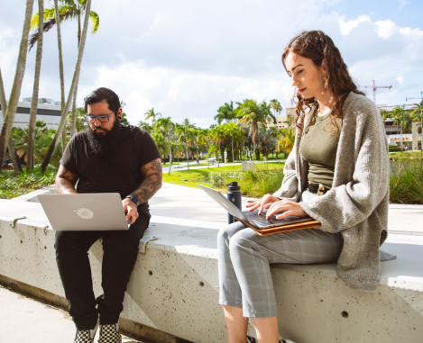 Two college students working on laptops